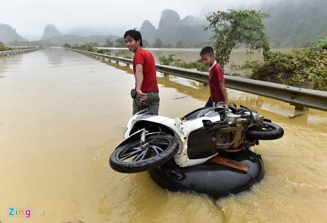 Do phương tiện không thể di chuyển, người dân phải thuê các thanh niên dùng phao kéo qua với giá 100.000 đồng/lượt.