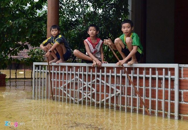 Những đứa trẻ ngồi trên tường rào chơi trong khi xung quanh đã ngập trắng.